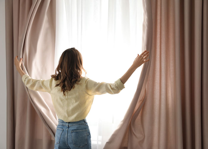 Mujer abriendo unas cortinas